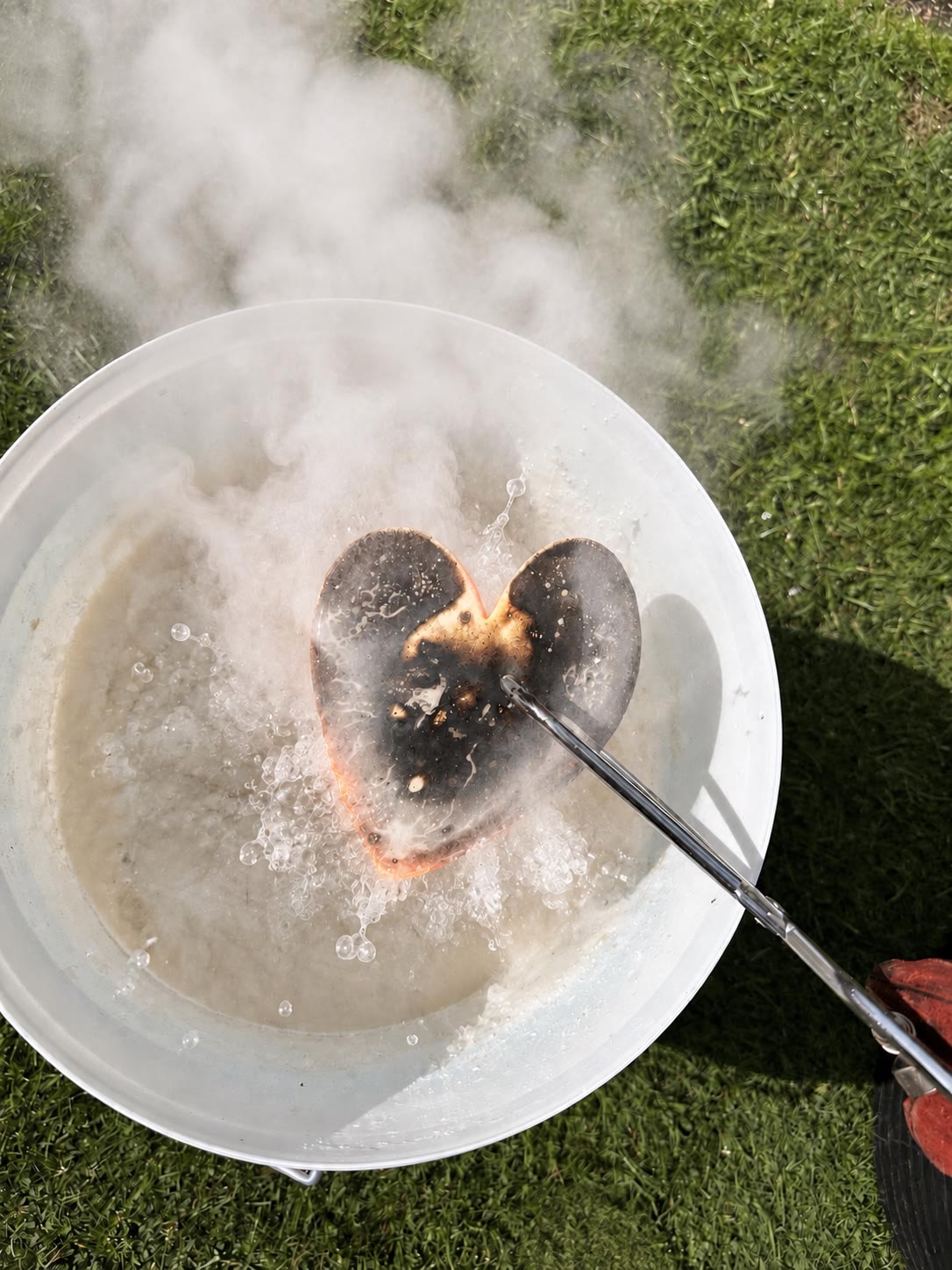 A red-hot ceramic heart steaming as it is dipped into an Obvara mixture